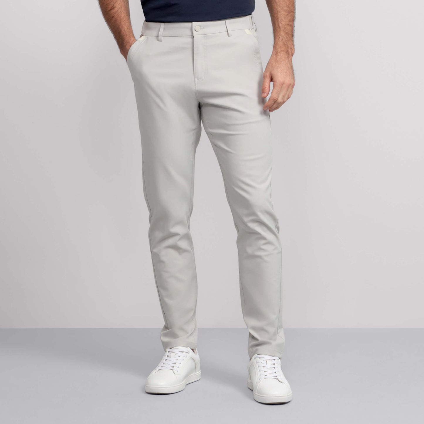 A person models the Jack Archer Jetsetter Tech Pant Straight Fit in Sand Stone, standing against a plain light gray background with hands in pockets and upper torso partially out of frame.