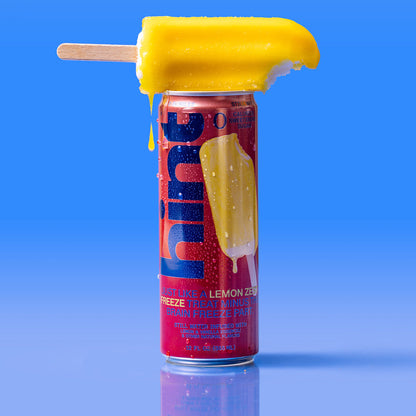 12 oz lemon zest flavored Hint Water can with a melting lemon popsicle balanced on top against a blue background